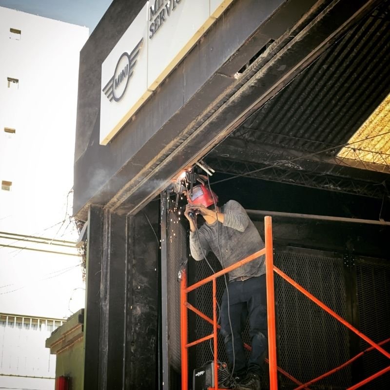 Soldadura de guía superior en portón curvo-corredizo. Corrección y soldadura de la guía superior de un portón curvo-corredizo en una empresa. El trabajo se realizó en altura con equipo de andamiaje para asegurar una reparación precisa y segura. Trabajo realizado por HERREELEC.